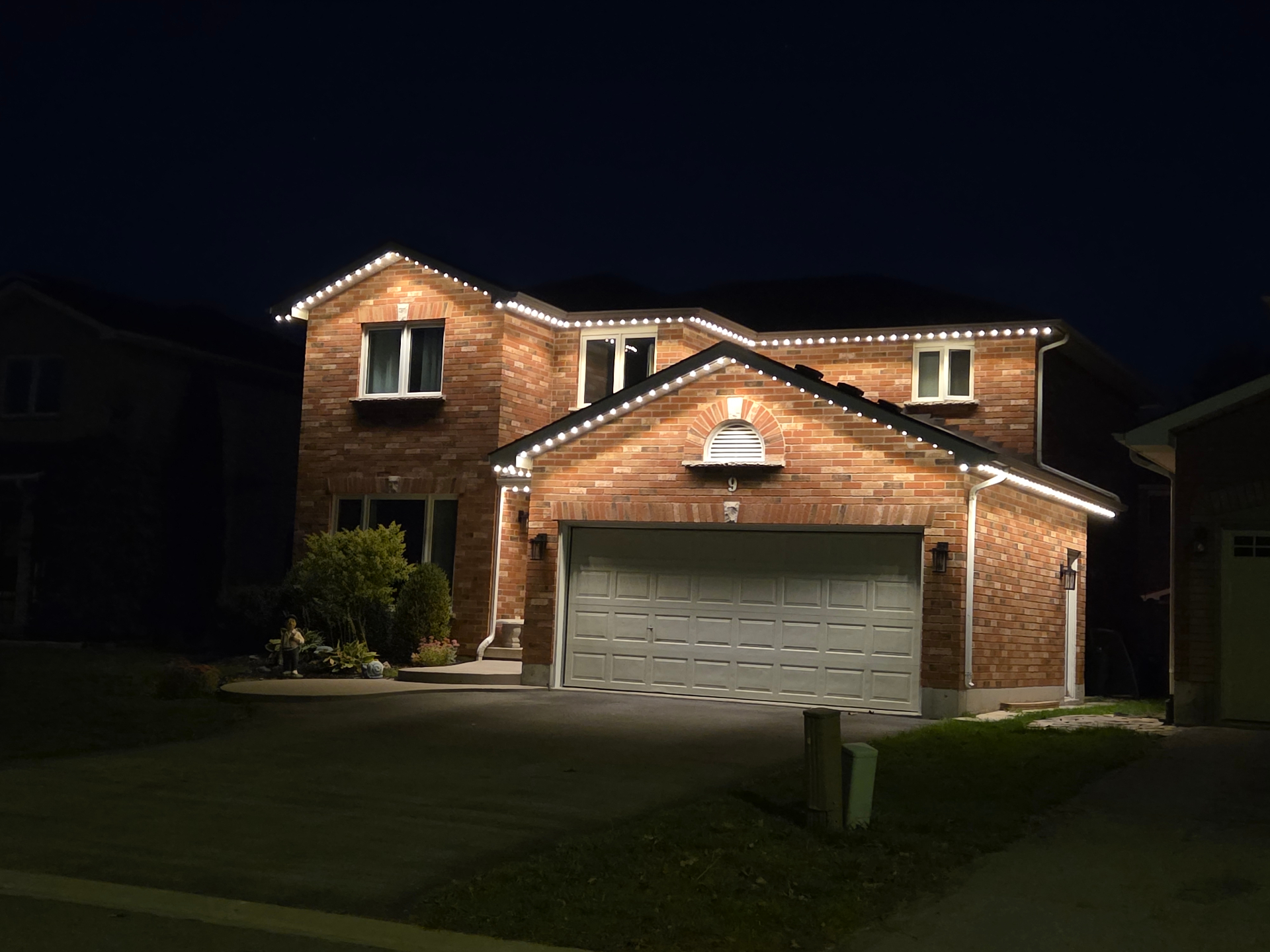 Two-storey brick Belleville home at dusk with warm white permanent LED roofline lighting