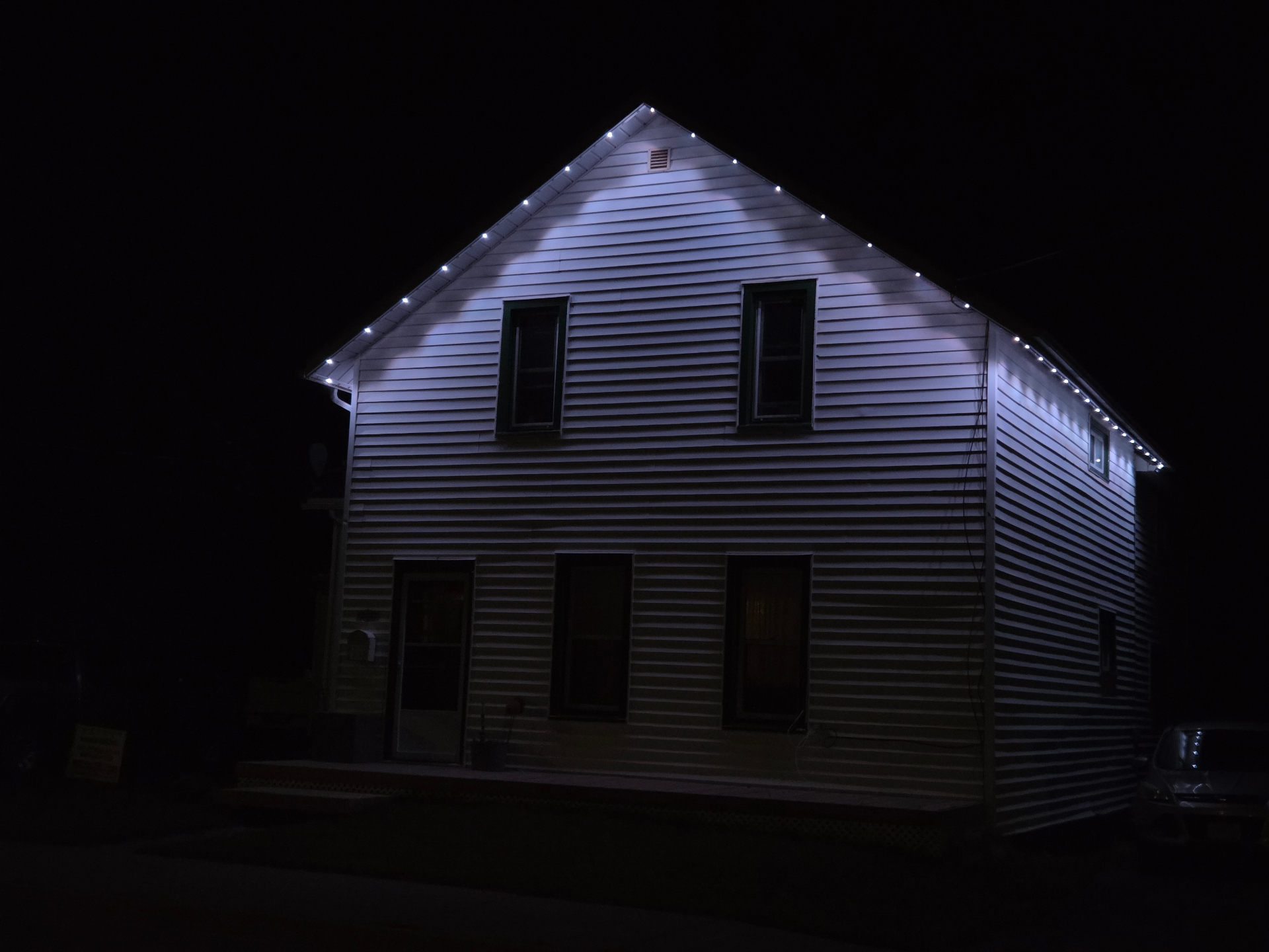 Gable end and eaves lit with warm white permanent LED lights at night