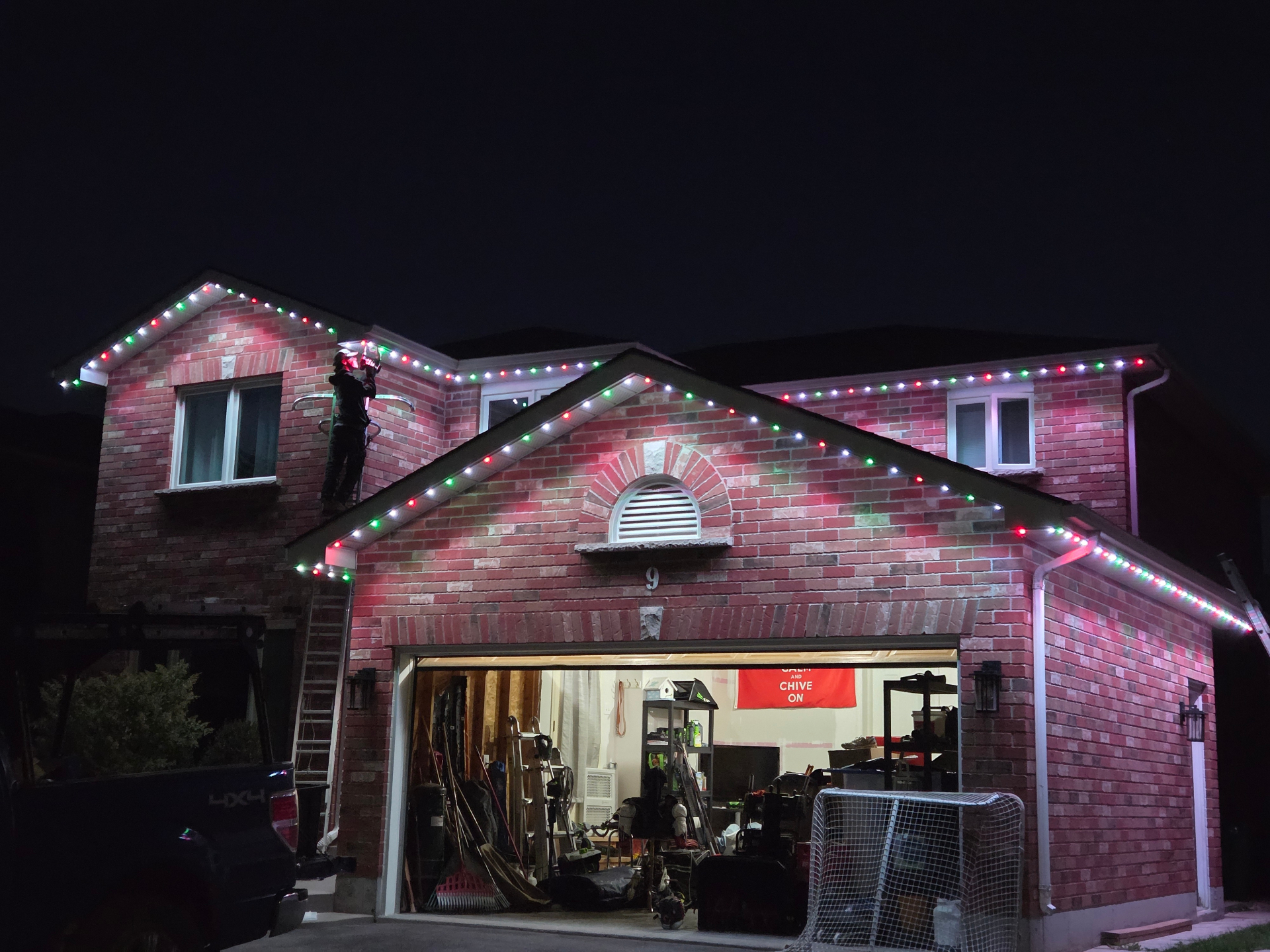 Warm Wishes crew finishing the red, green and white Christmas scene on a Belleville home